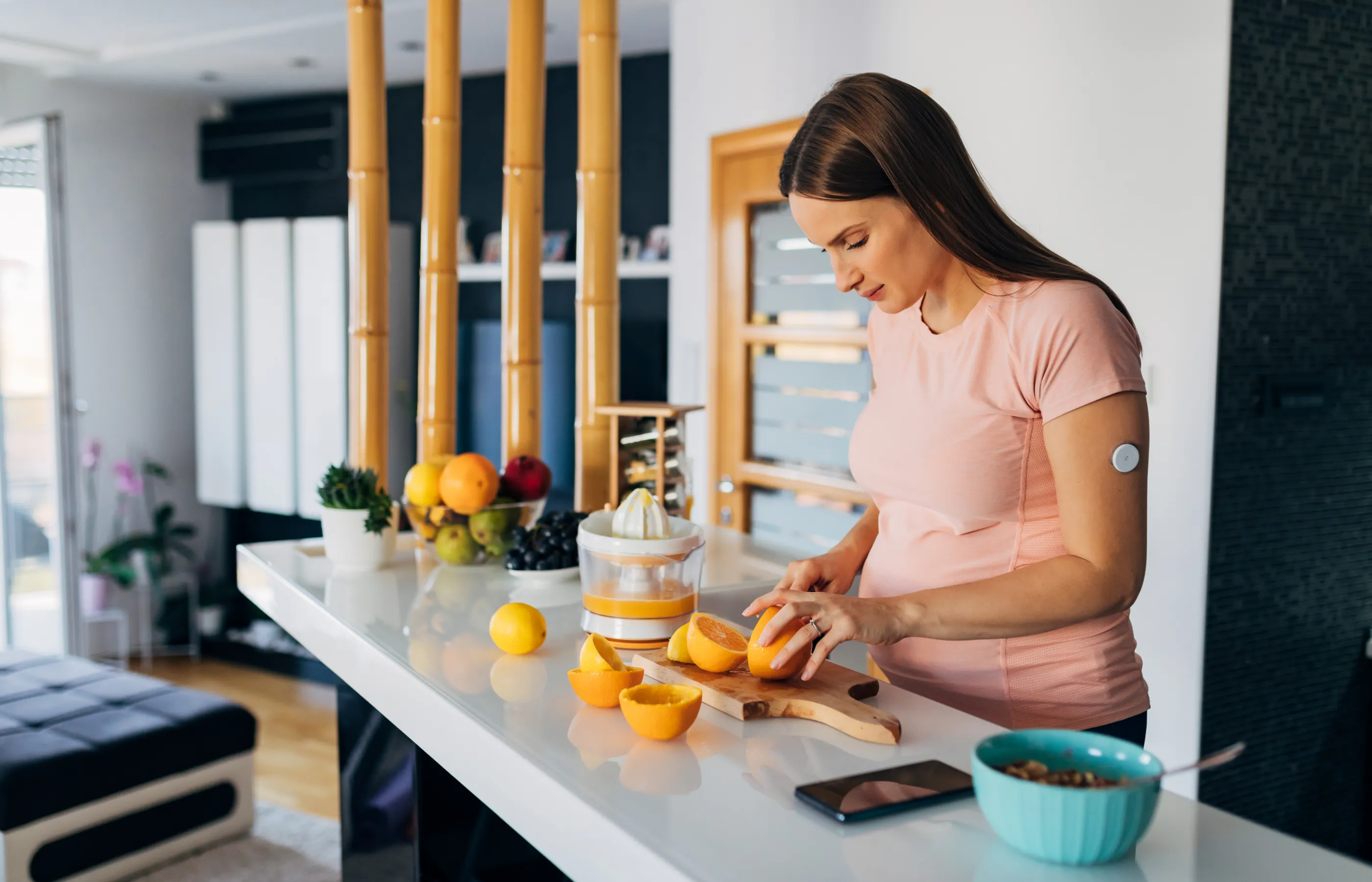 A woman, wearing a glucose tracker, is preparing food in the kitchen. 