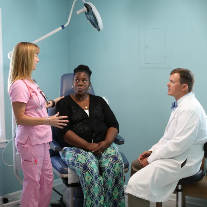 Patient, nurse, and provider in exam room discussing treatment. 