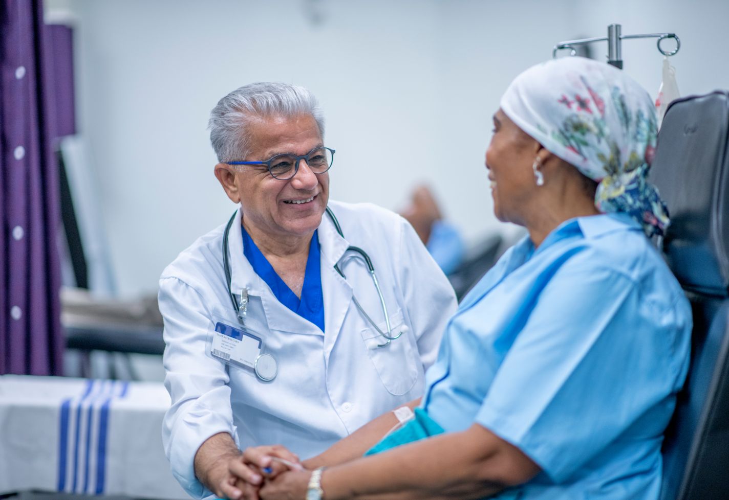 A doctor smiling while speaking with a female cancer patient.
