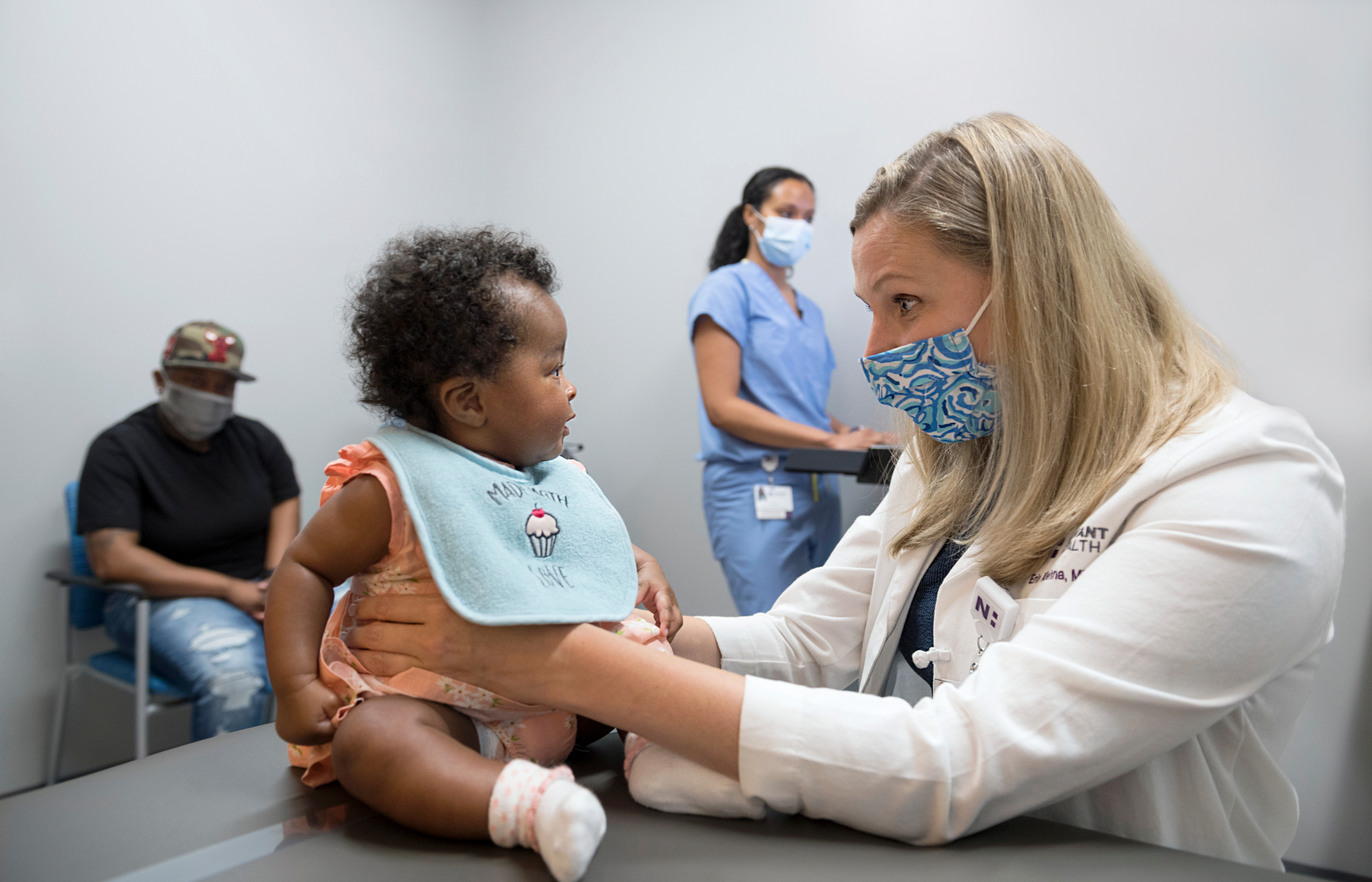 Dr. Kiehna treats a baby while the baby's father and a nurse watch.