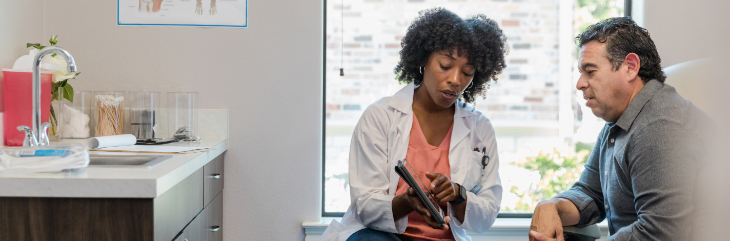 Female doctor with a male patient discussing healthcare information on a tablet