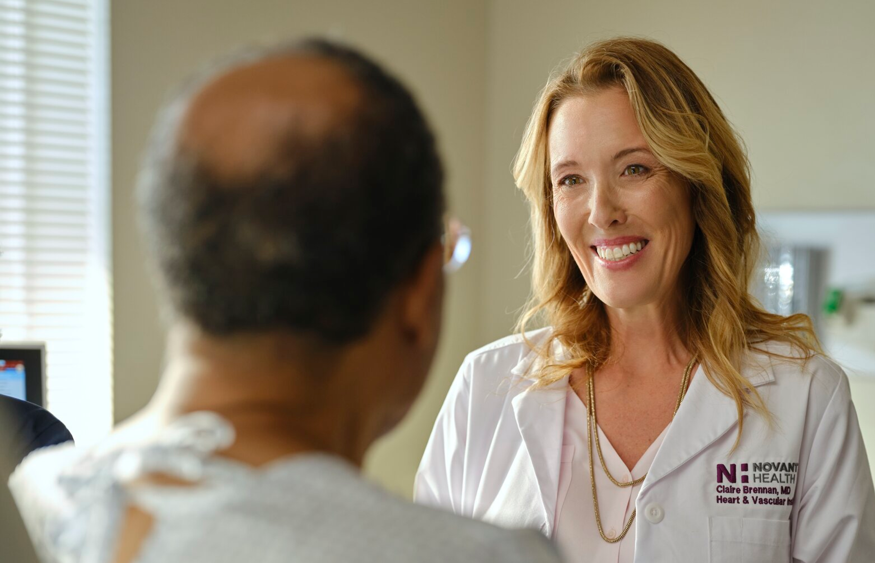 Doctor Brennan smiles while she speaks with a male patient.