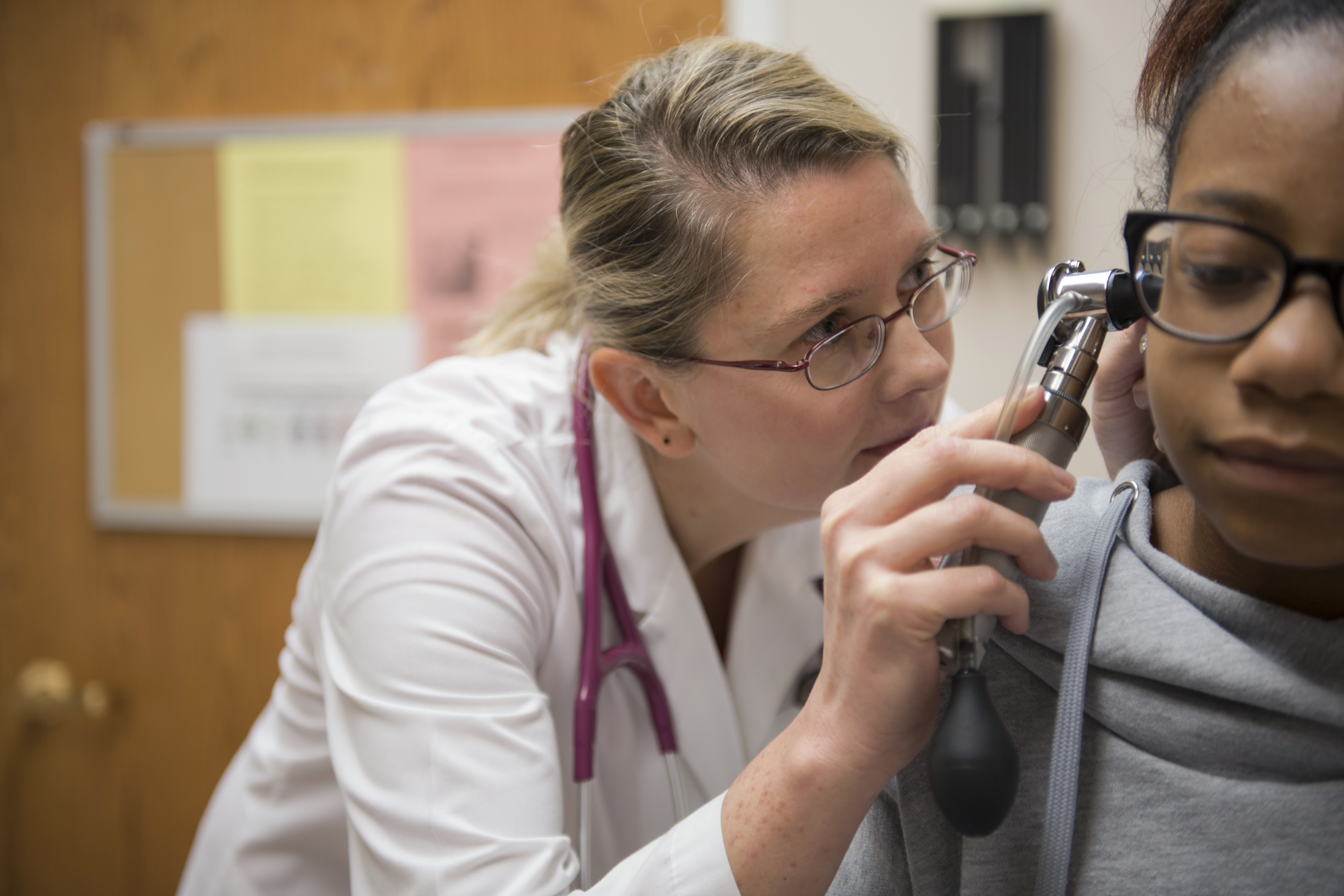 Dr. Magdalena Bilska is looking into the ear of a young patient. 