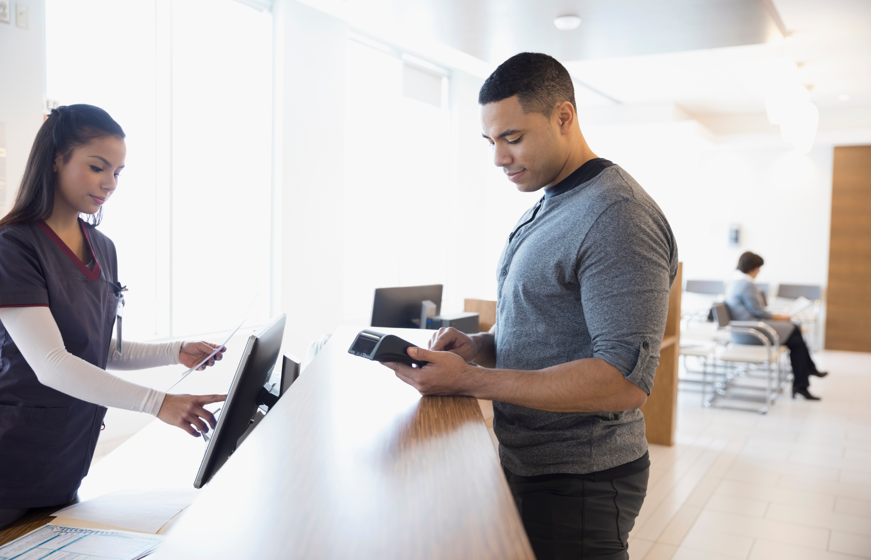 A male patient checking in at a clinical desk.