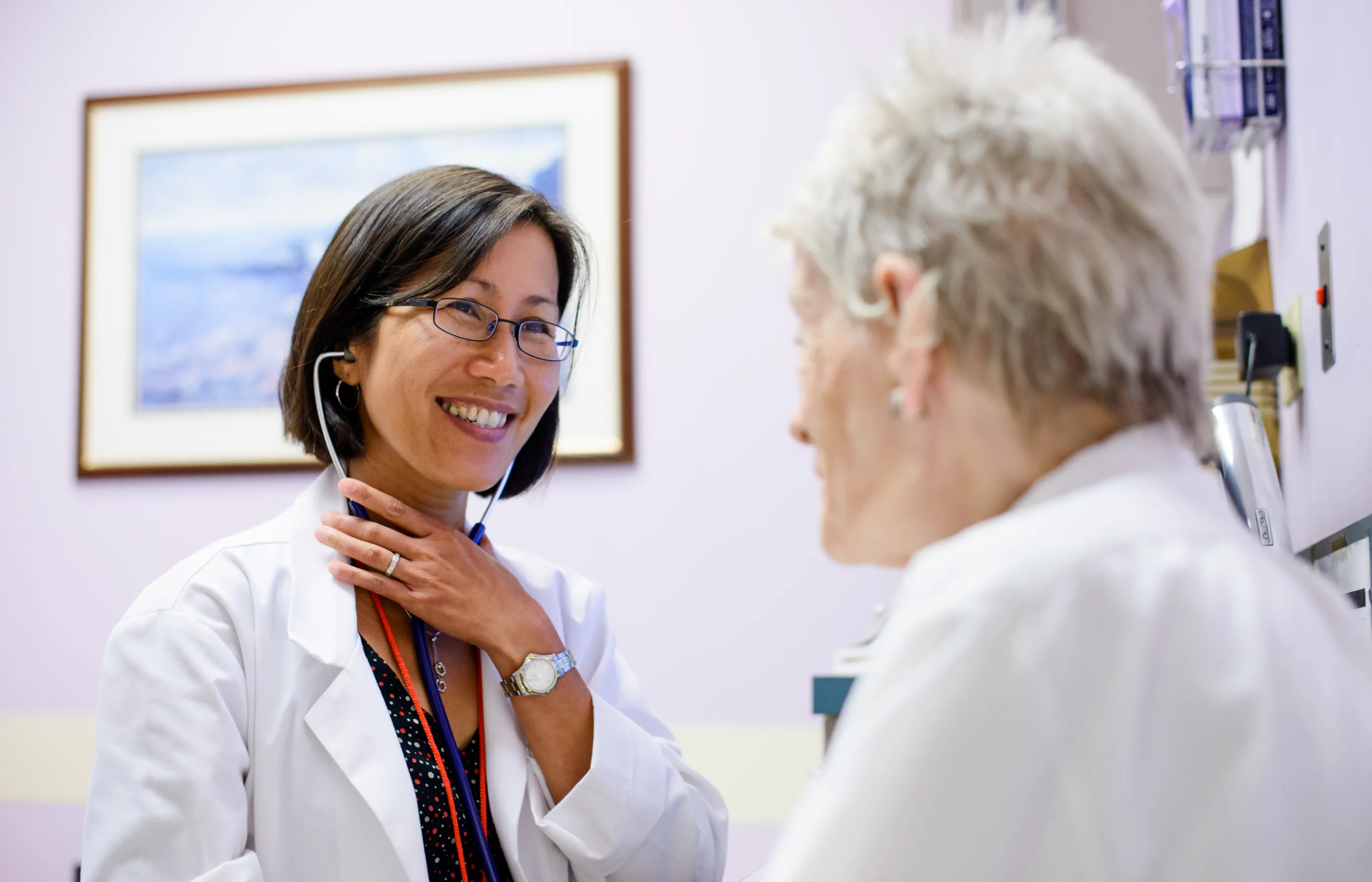 A smiling female doctor listens as an older female patient discusses her health.