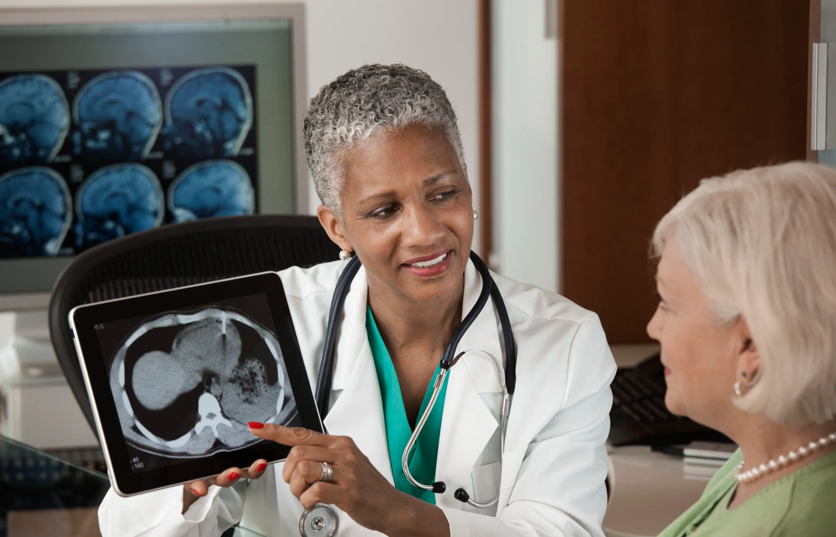 A health care provider is reviewing brain imaging scans with a senior patient. 