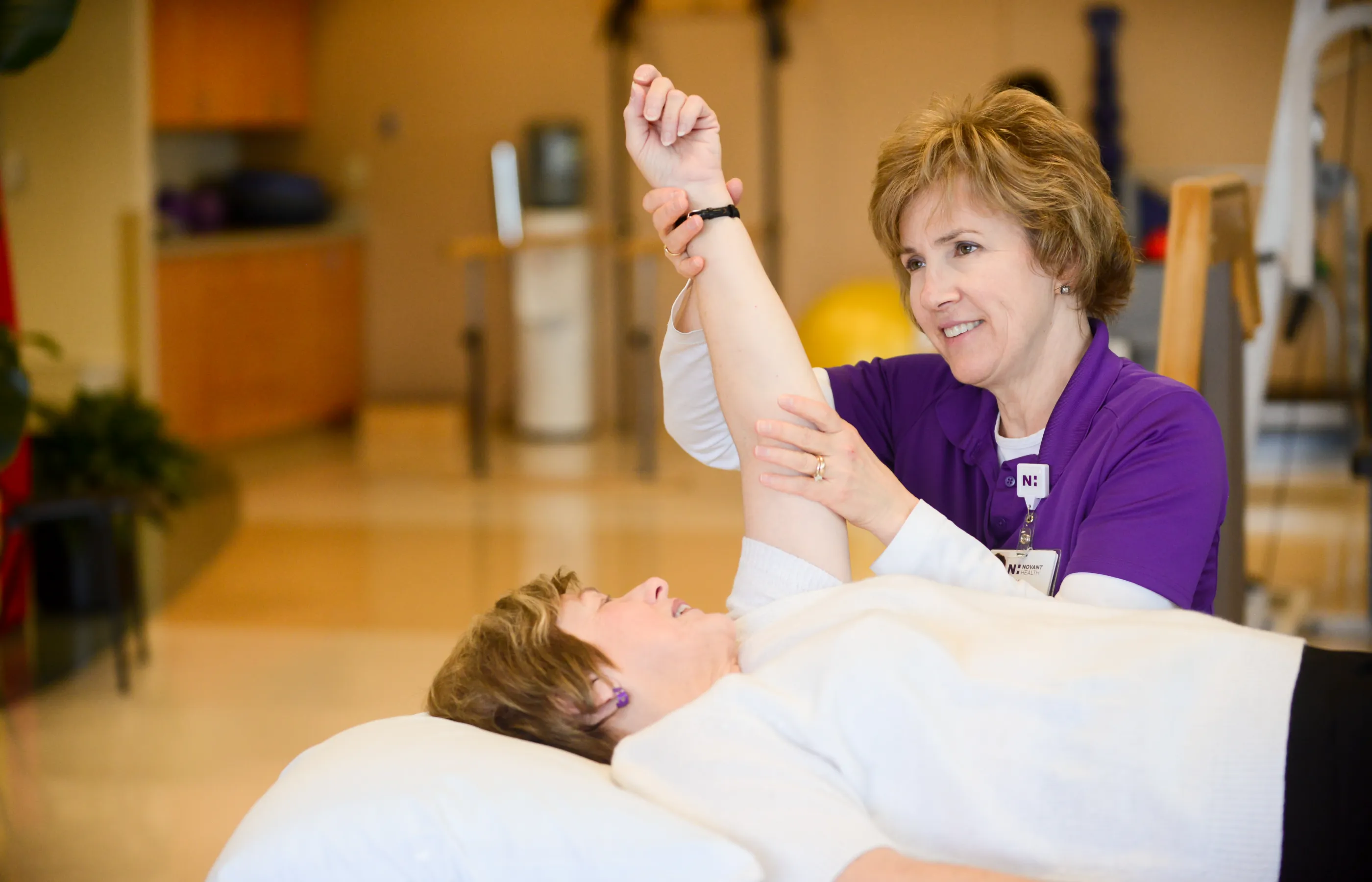 A Novant Health team member is assisting a patient as they work through physical therapy exercises. 