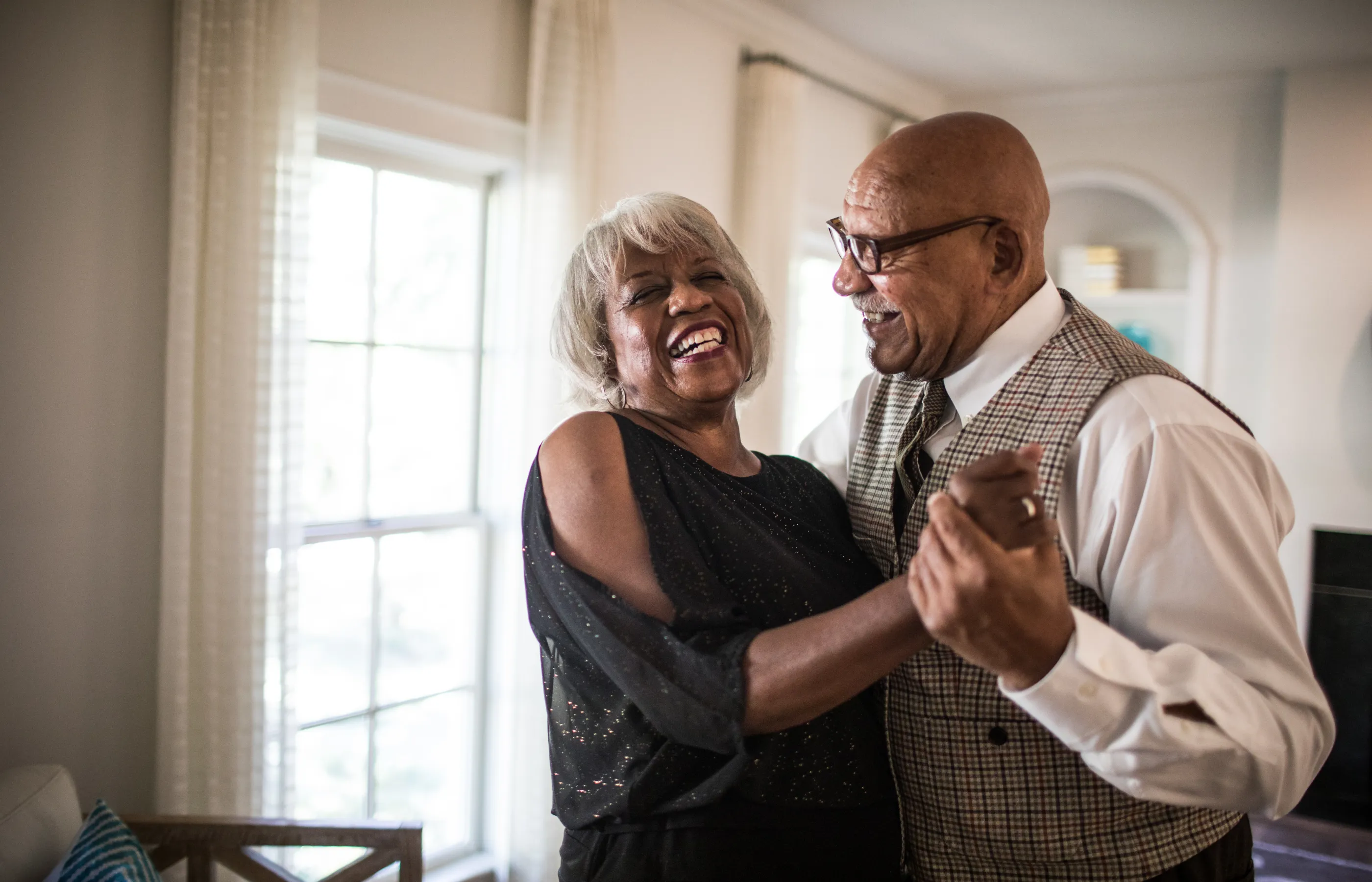 A senior couple is dancing and laughing together.