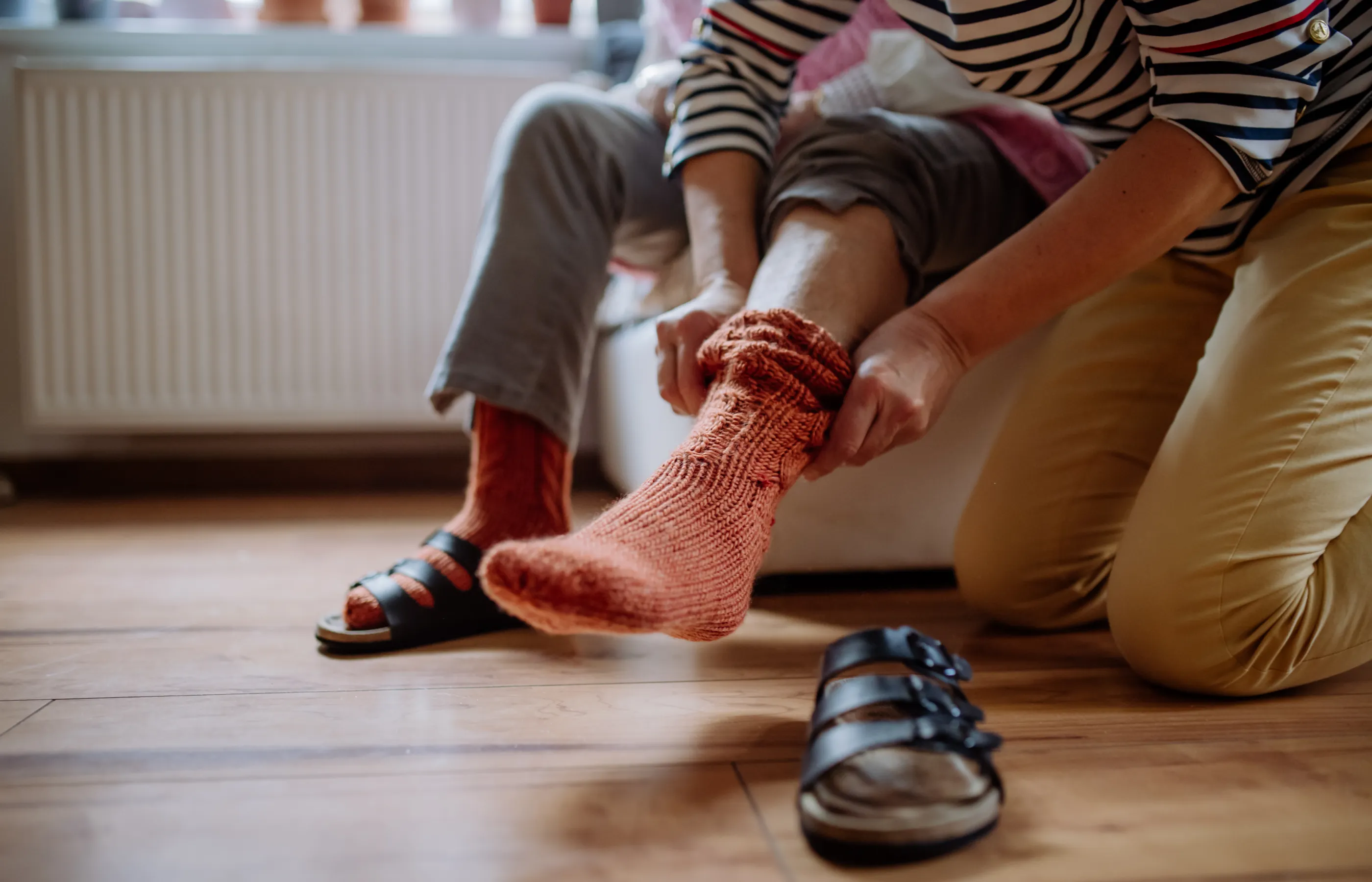 A caregiver is assisting a senior by putting on her socks. 