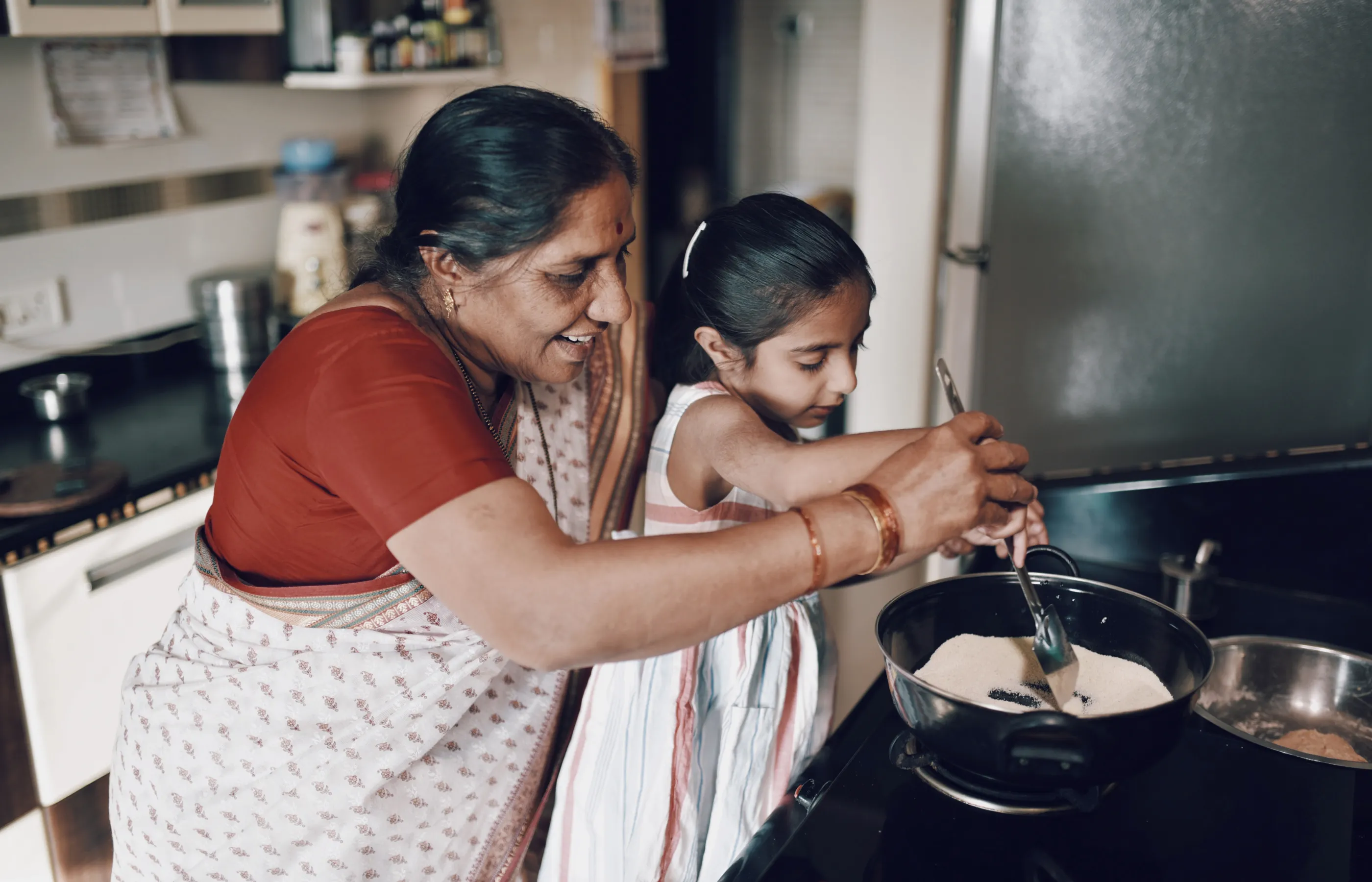 A young girl is cooking with her grandmother. 