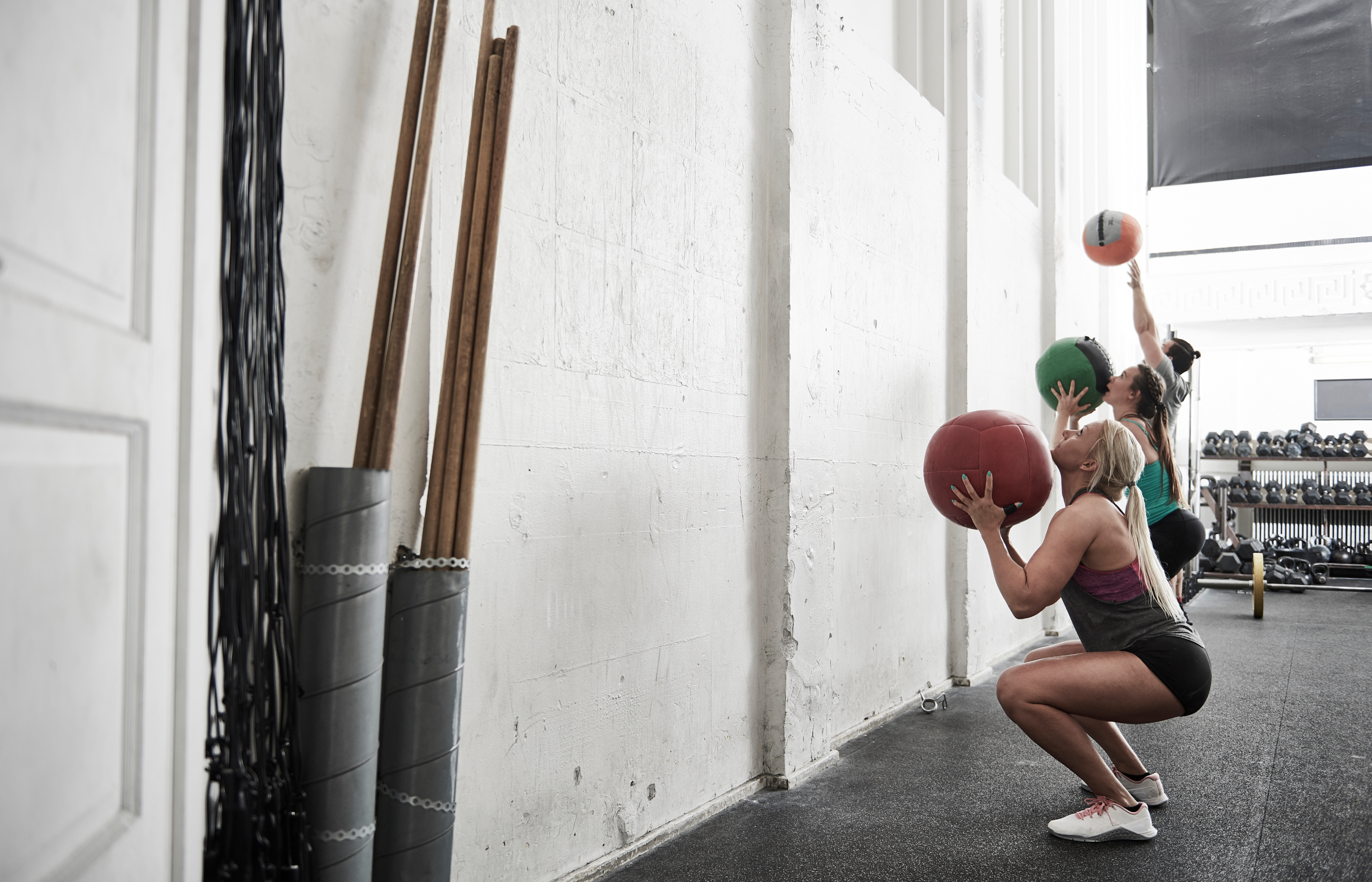 A group of women are training with weighted medicine balls. 