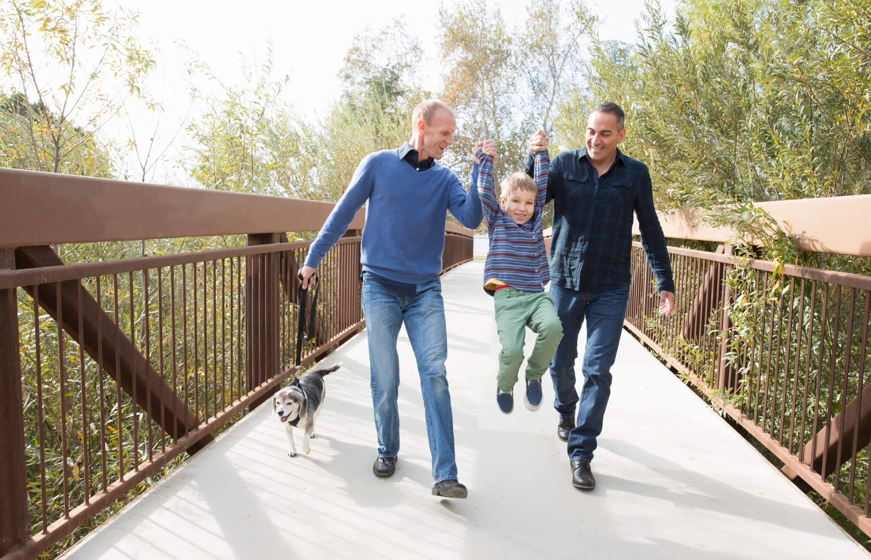 LGBTG family walking over a bridge smiling child.
