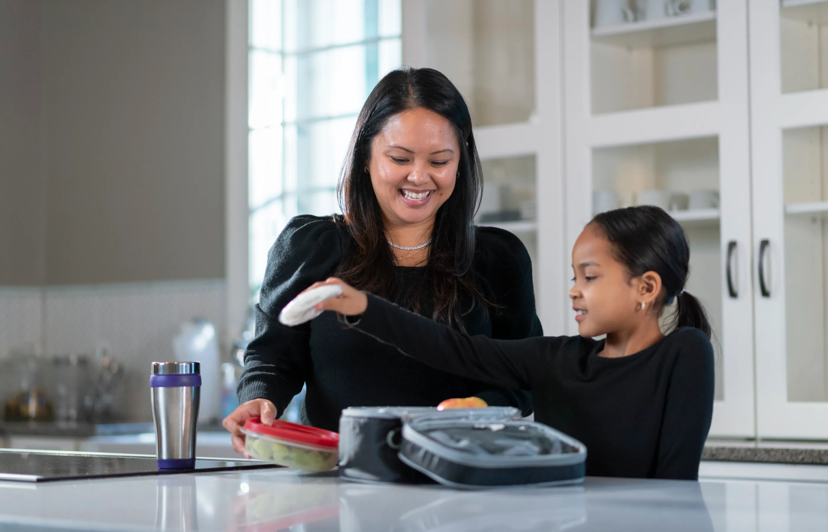 A mother and daughter in the kitchen talking while preparing food.
