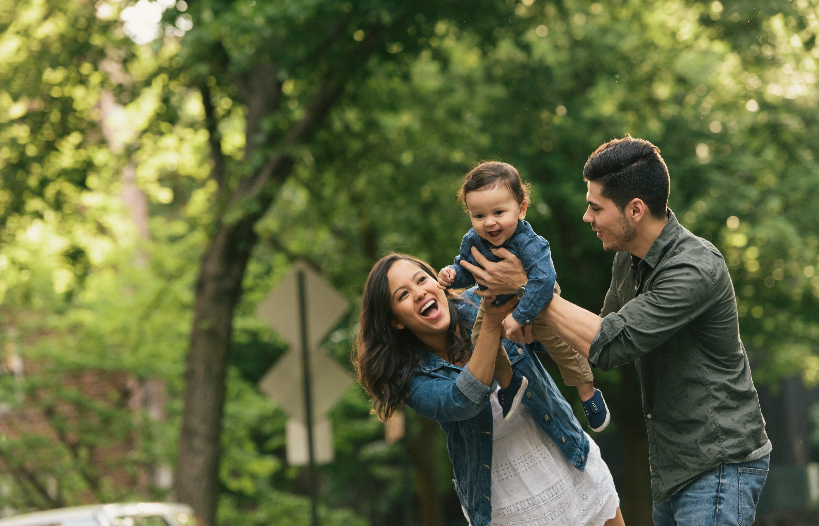 Happy parents enjoying family time outside with their toddler.