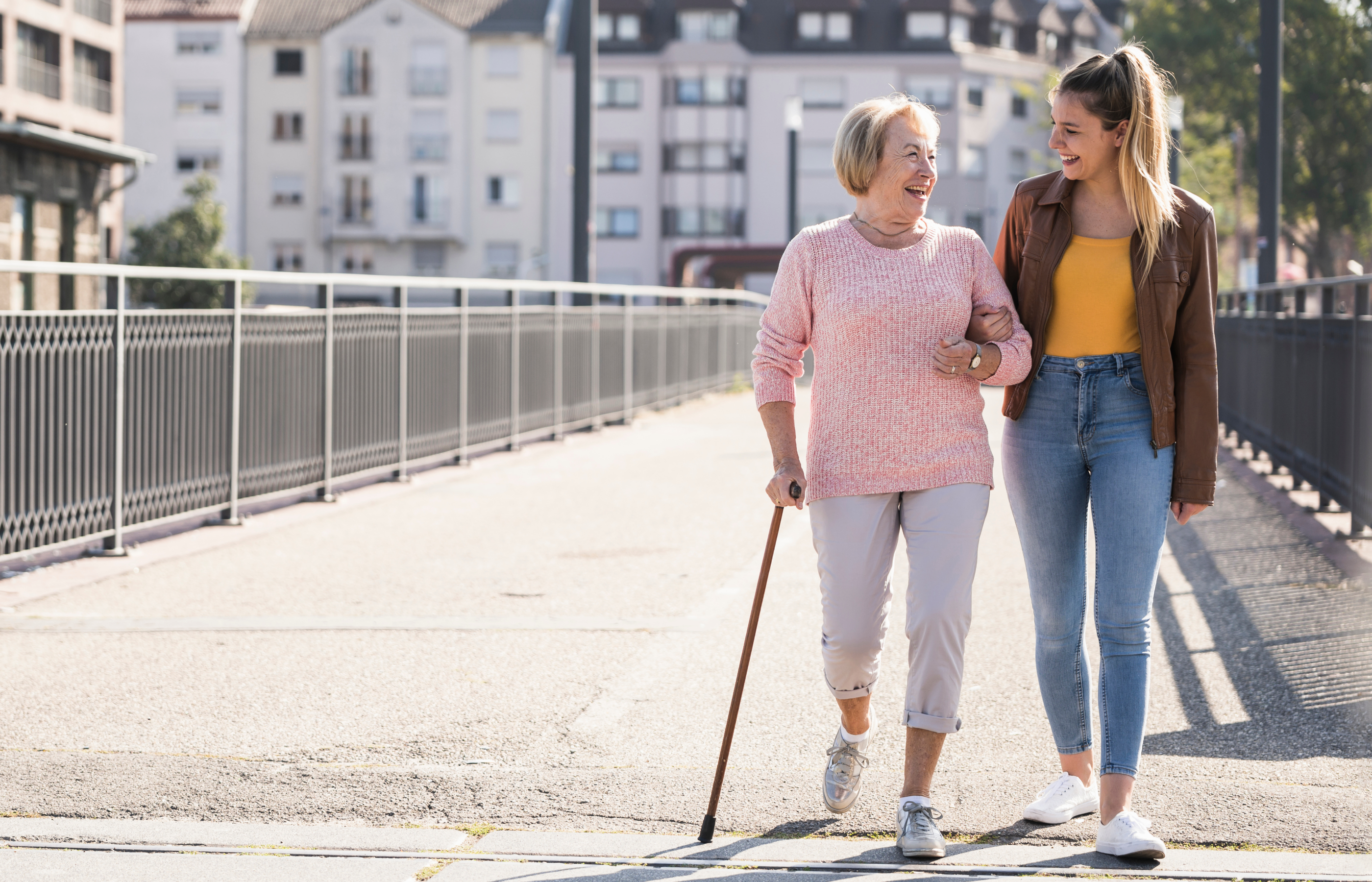 Two adult women walking on a pier on a sunny day.