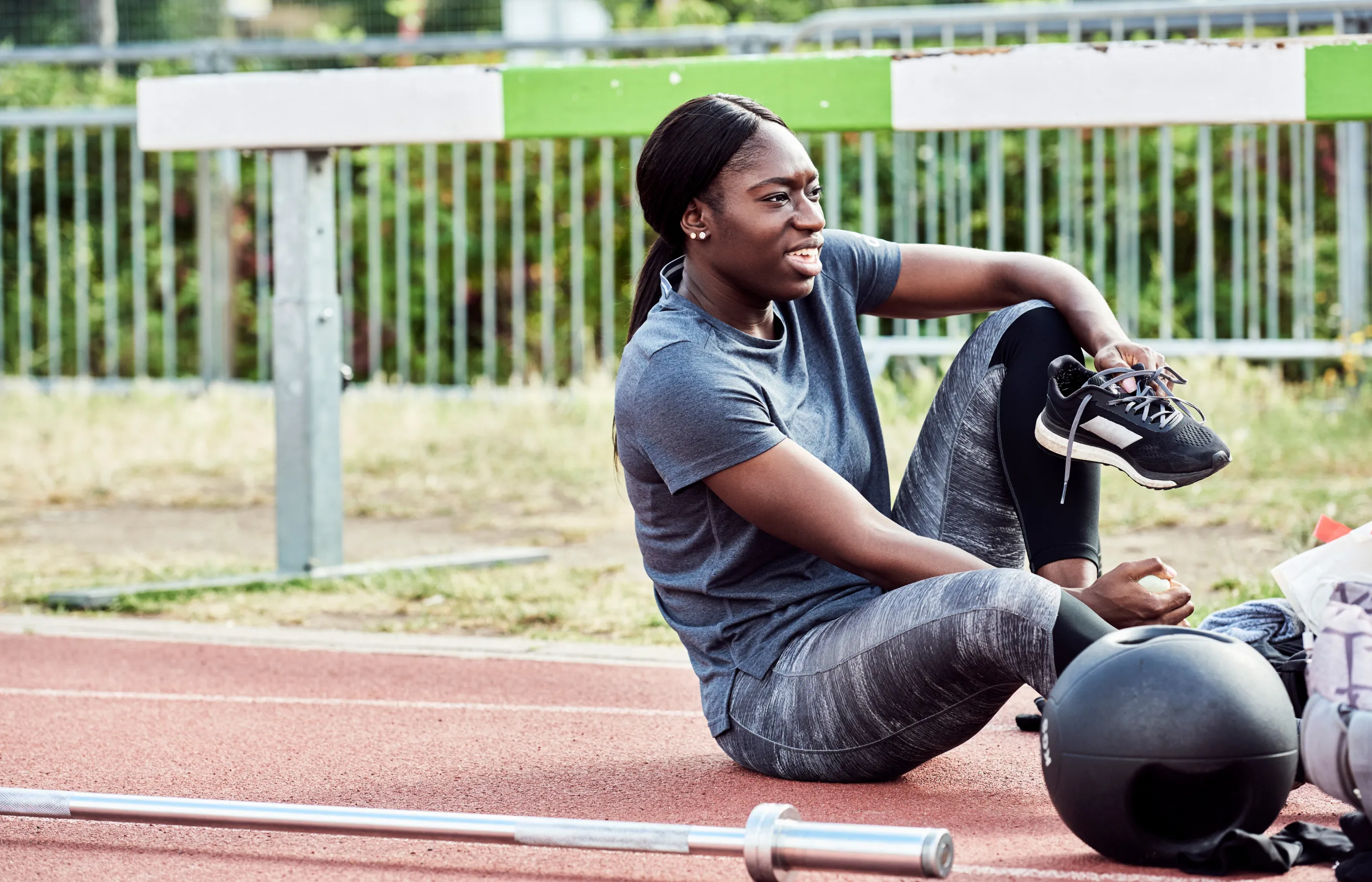 Athletic woman sitting on a track putting her shoes on to get ready for running.