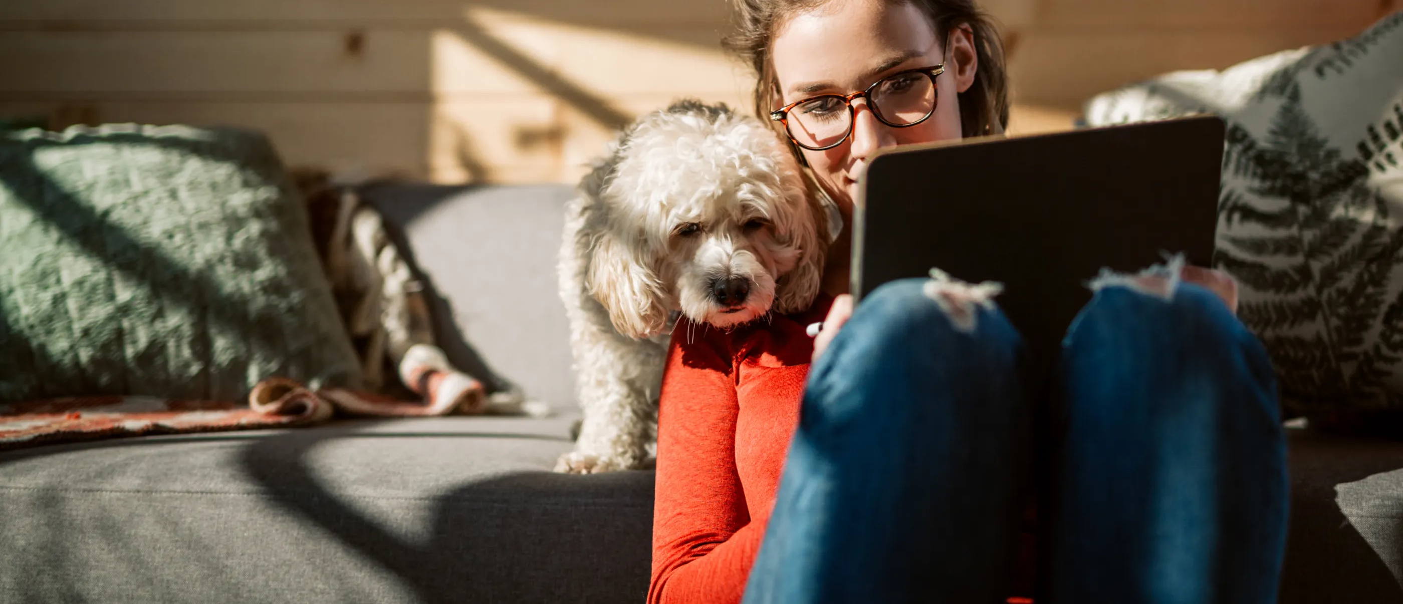 Woman using her tablet while sitting on the floor with her dog.