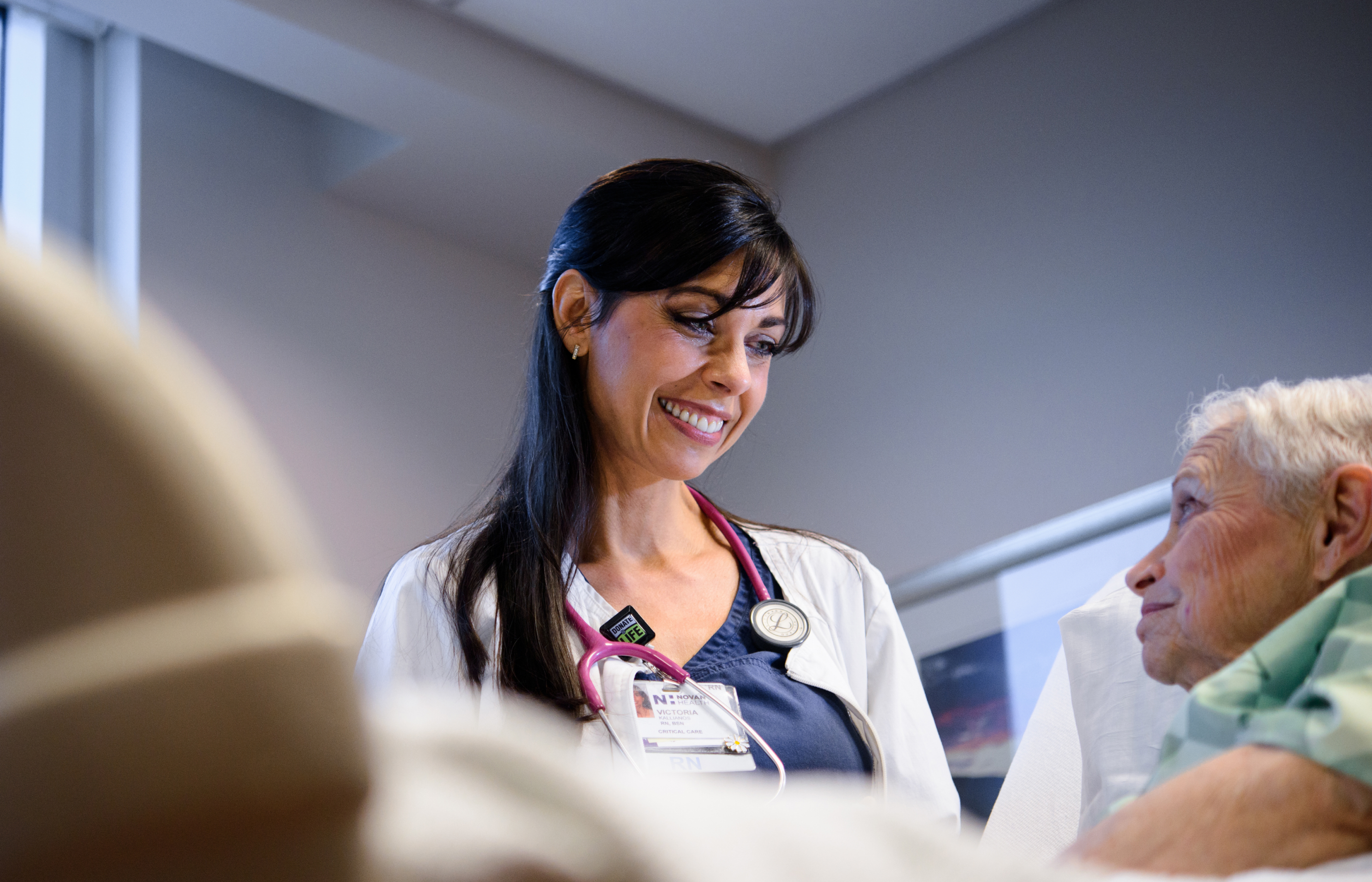 smiling nurse at an elderly patient's bedside