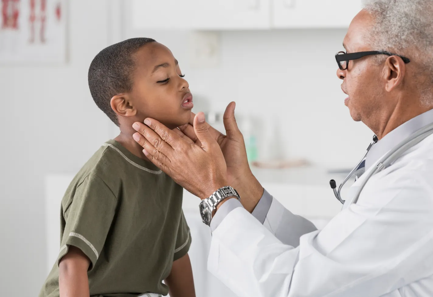 A doctor is examining the neck of a young boy.