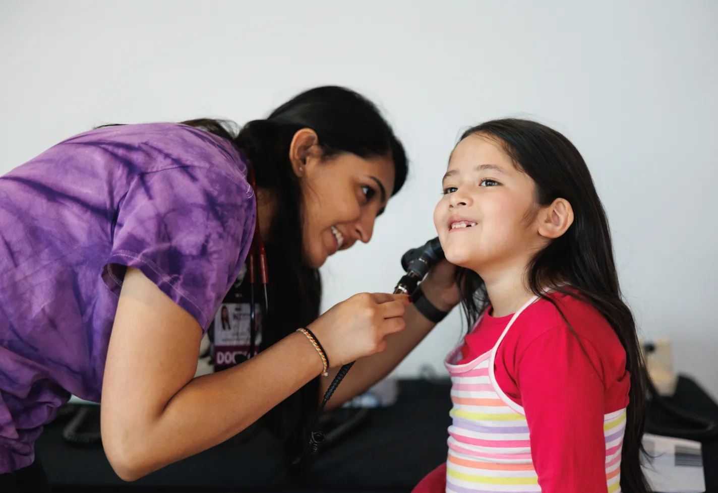 A Dr. Patel is examining a young childs ear.