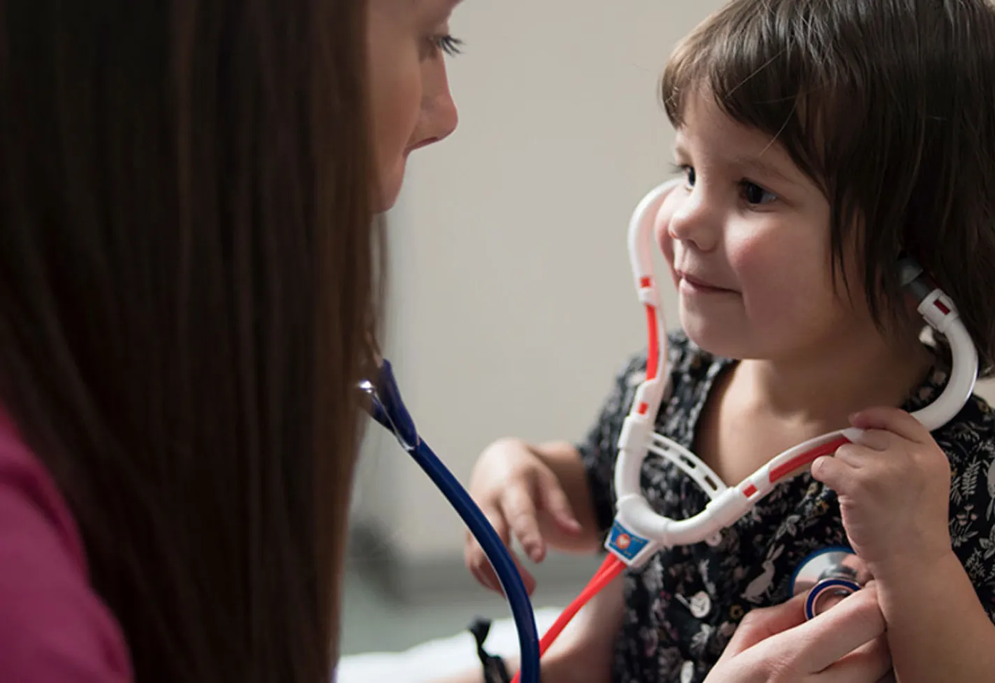 A young girl playing with a toy stethoscope. 