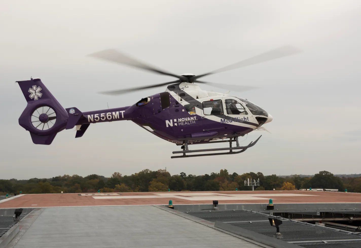 A Novant Health helicopter is hovering over a launch pad. 