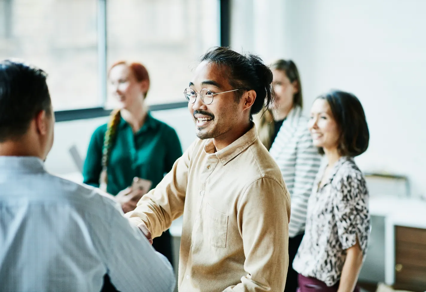 A man is shaking the hand of a colleague as he greets a group of people