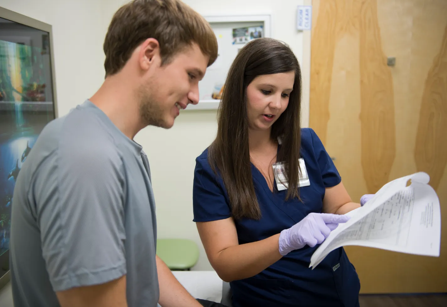 A Novant Health nurse is reviewing paperwork with a male patient. 