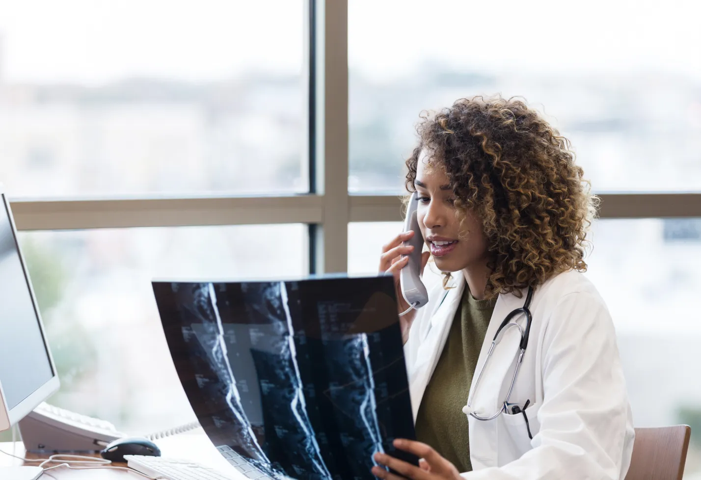 A health care provider is reviewing an x-ray while talking on the phone. 