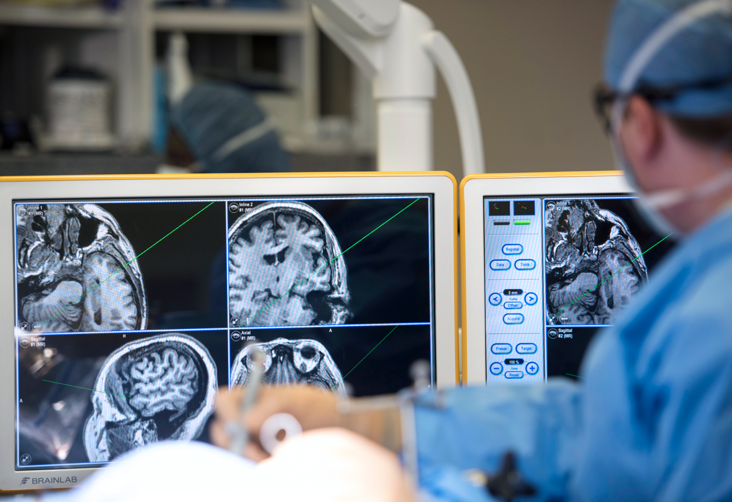 A brain surgeon looks at monitors while performing a procedure in the operating room.