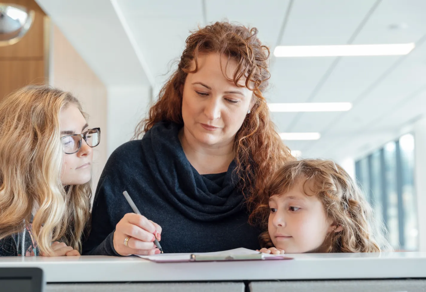 A mother and her daughters signing in at the clinic's reception desk 