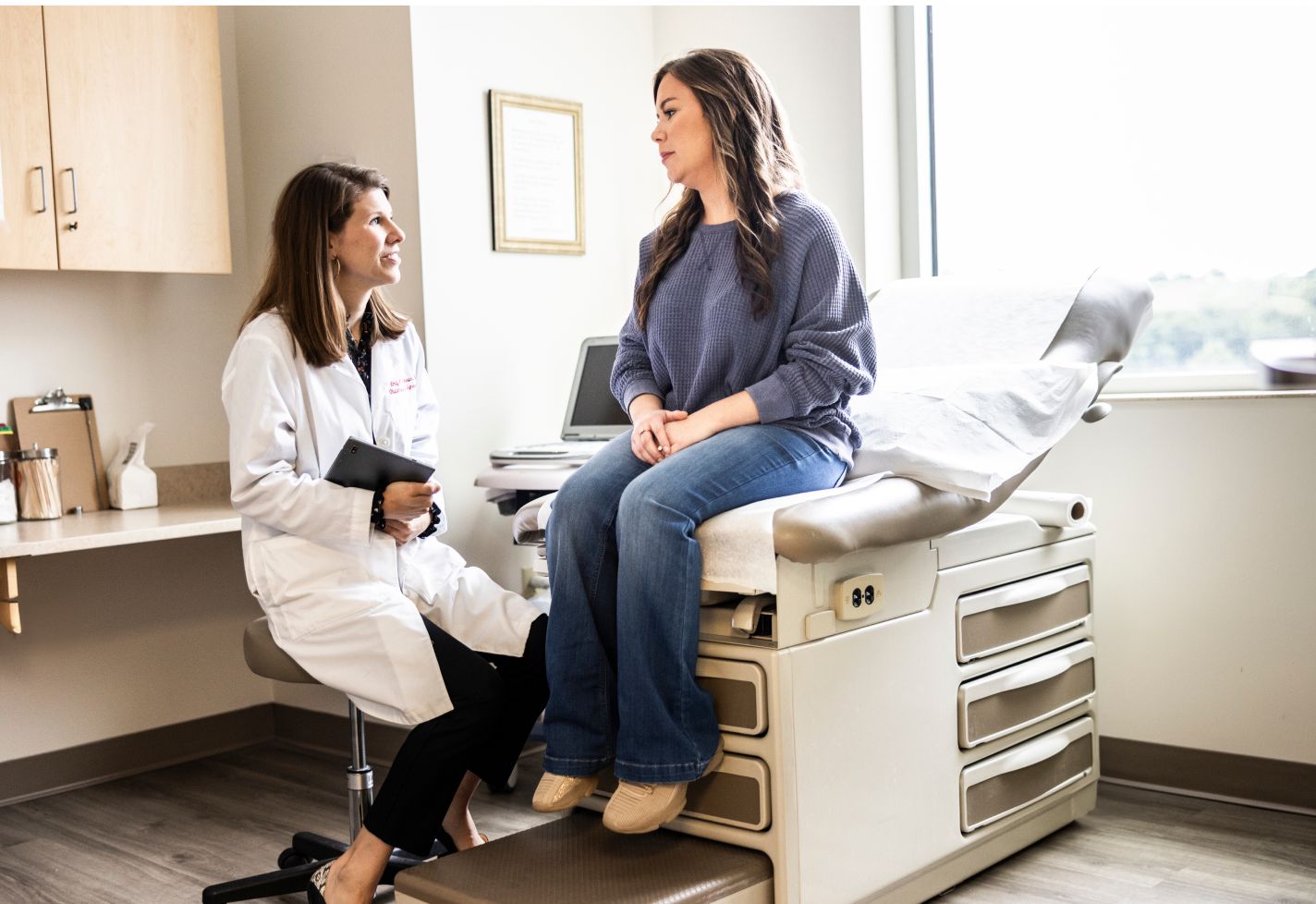 A female doctor exams a patient on a clinical exam table.