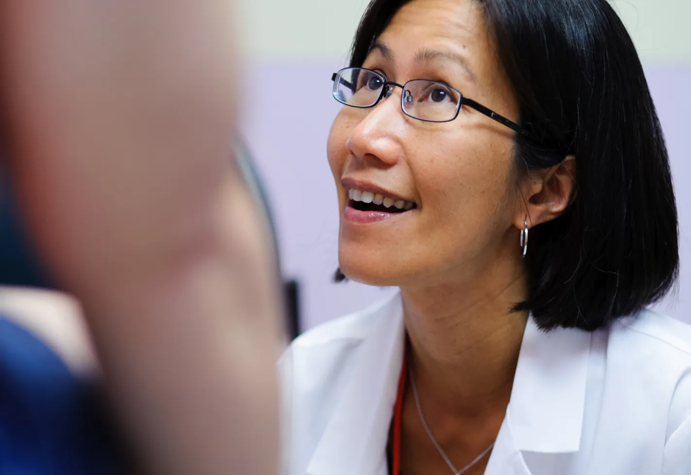 Woman provider looking up smiling as she exams a patient. 