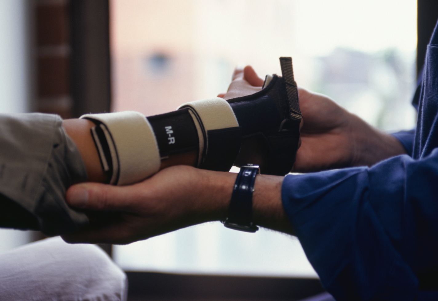 A person receiving wrist support from a medical professional, showing a brace on their arm.