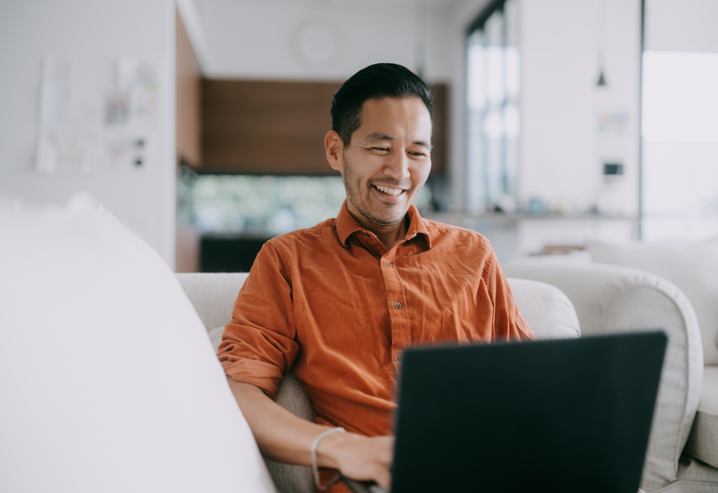 A man smiling while using a laptop.