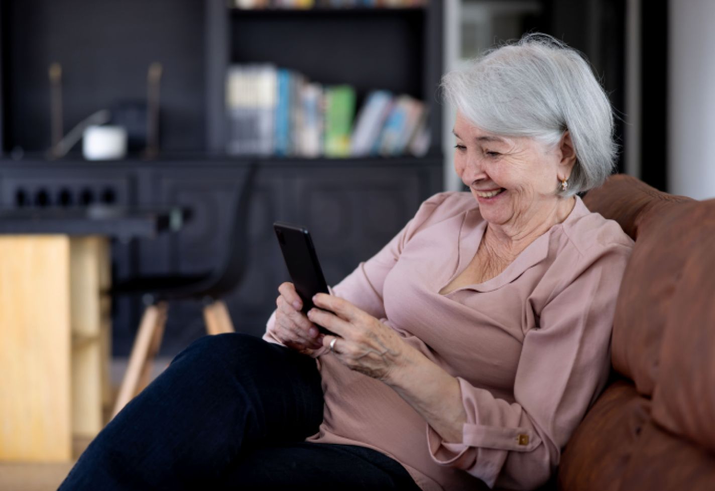A senior woman smiling while using her phone.