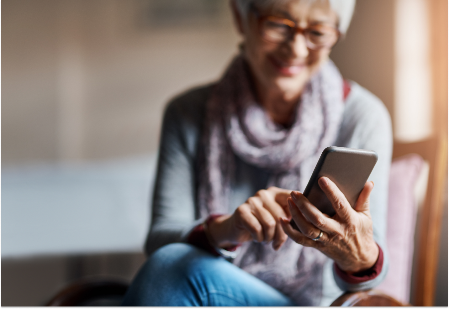 Woman sitting in a chair viewing and using her smartphone
