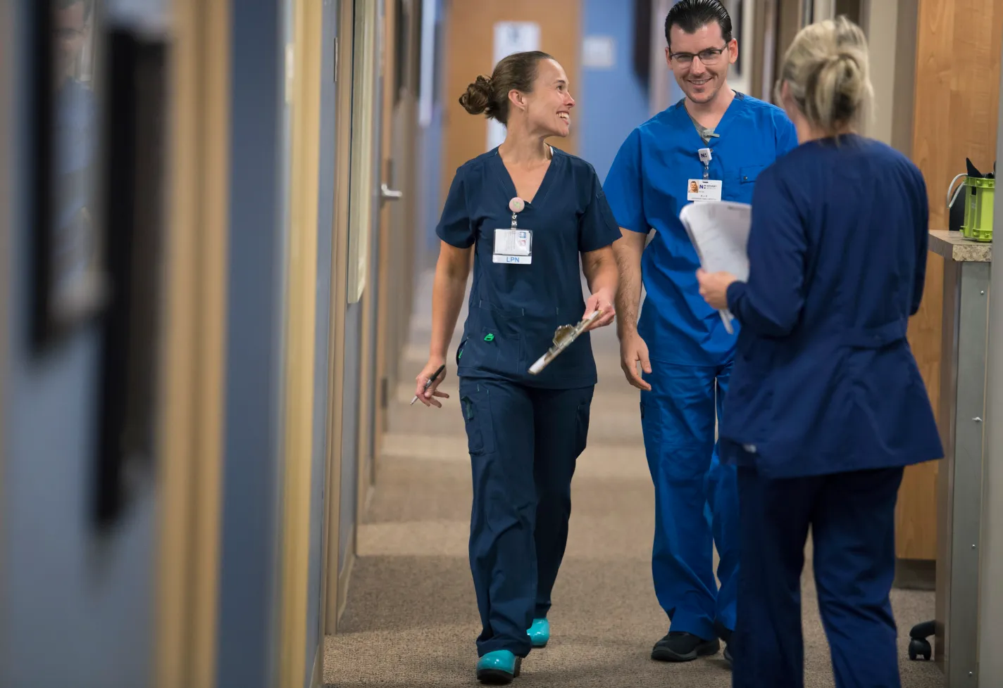 Three team members smiling while walking down a clinic hallway. 