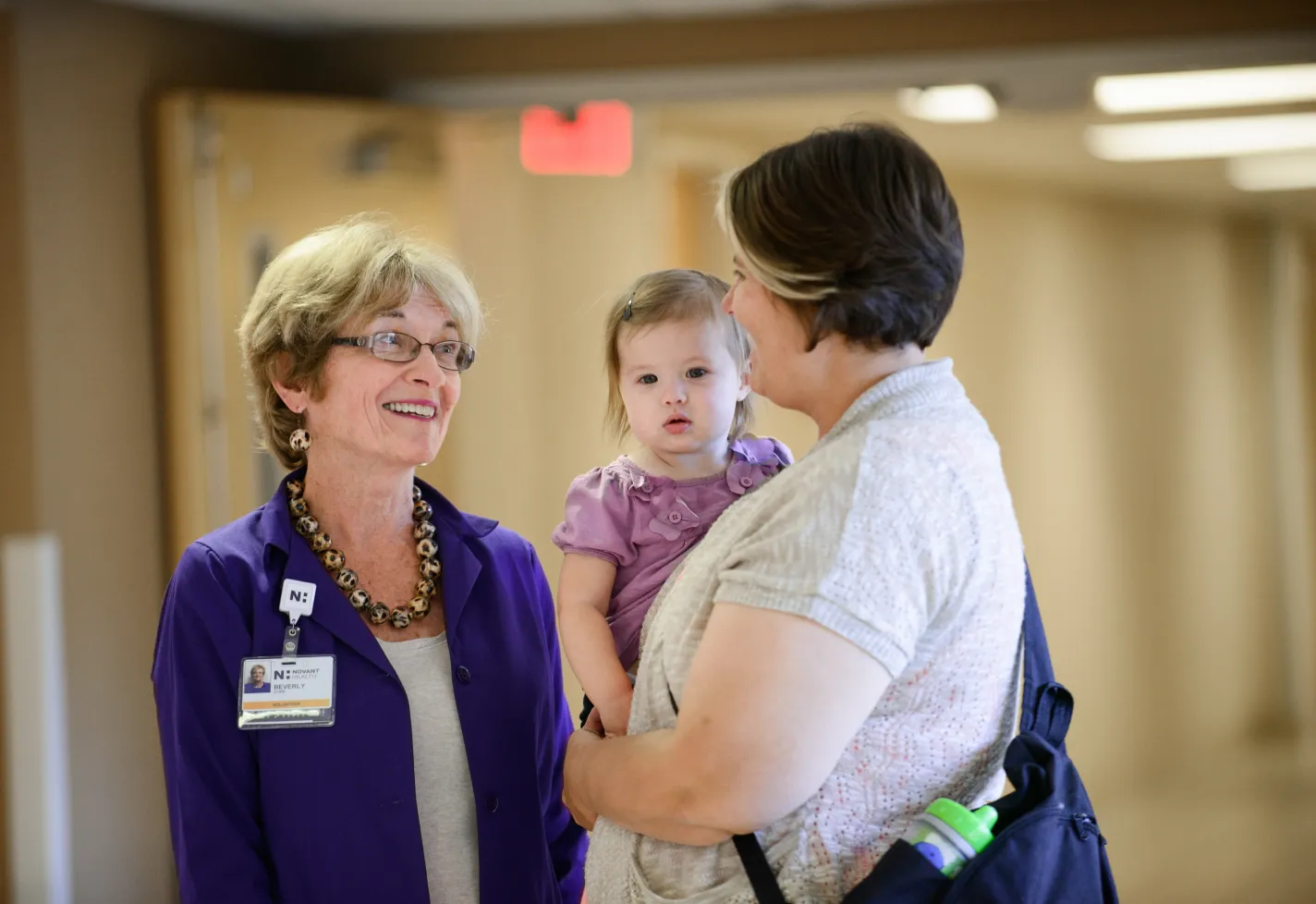 Novant Health volunteer meets with mother and child in pediatric hospital hallway
