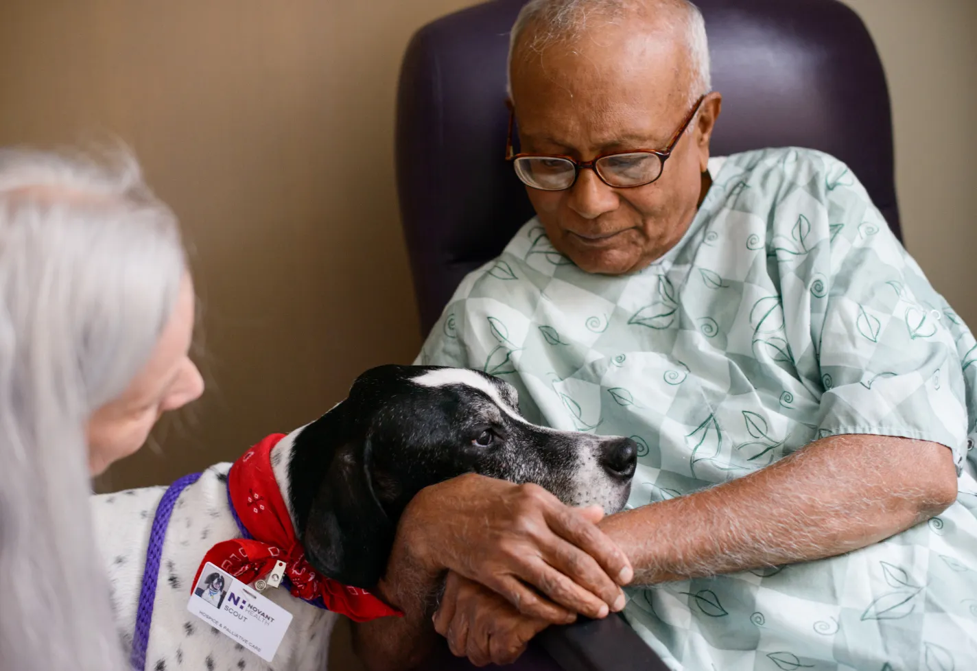 Volunteer with a service dog visits with a patient