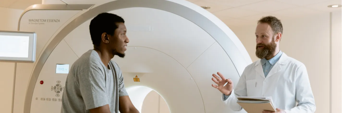 Male patient talking with a healthcare provider as they sit and prepare for an imaging scan. 