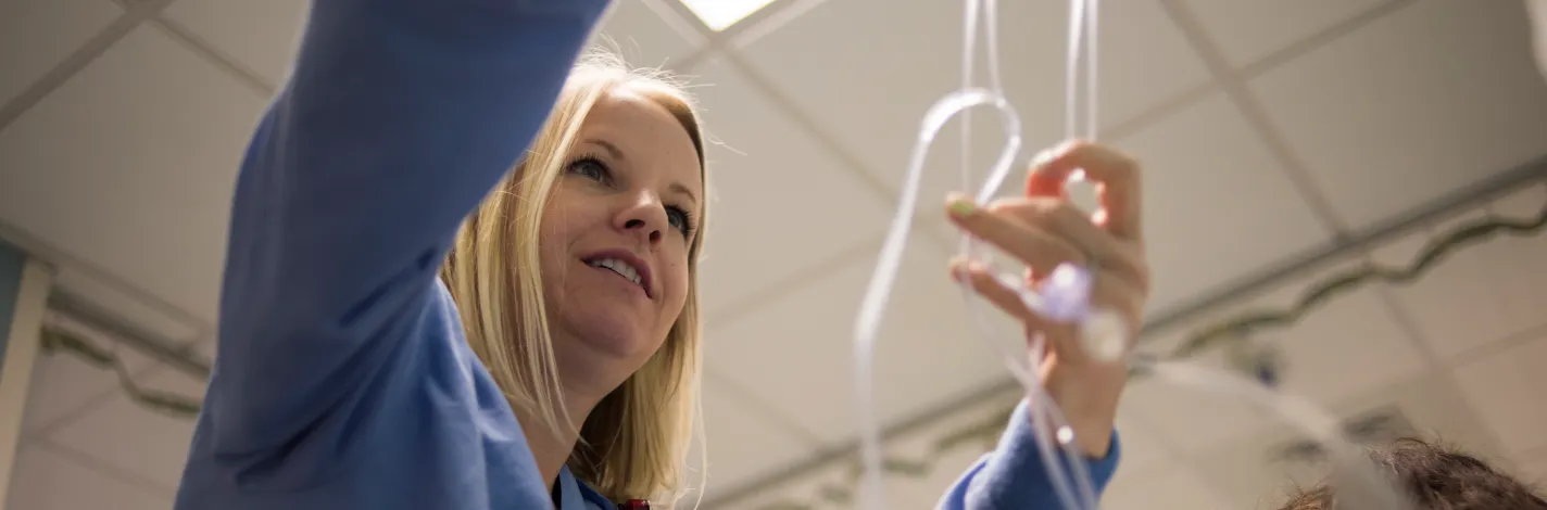 A Novant Health nurse is setting up fluids at a patients bedside before surgery. 