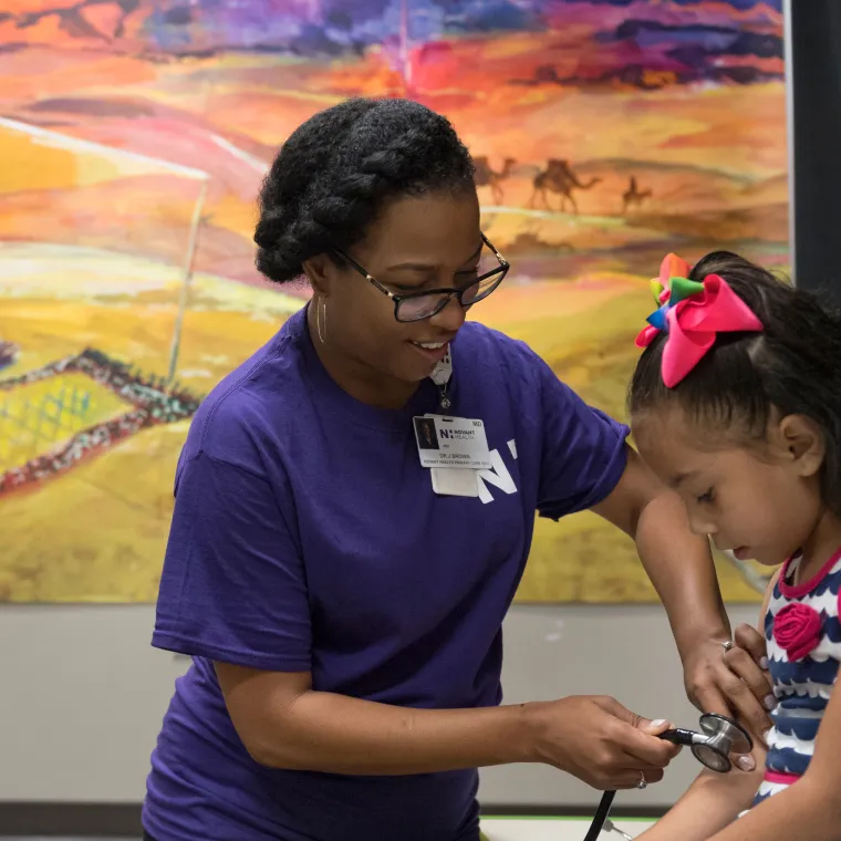 Novant Health's Dr. Brown is preparing to listen to a young girls pulse with a stethoscope. 