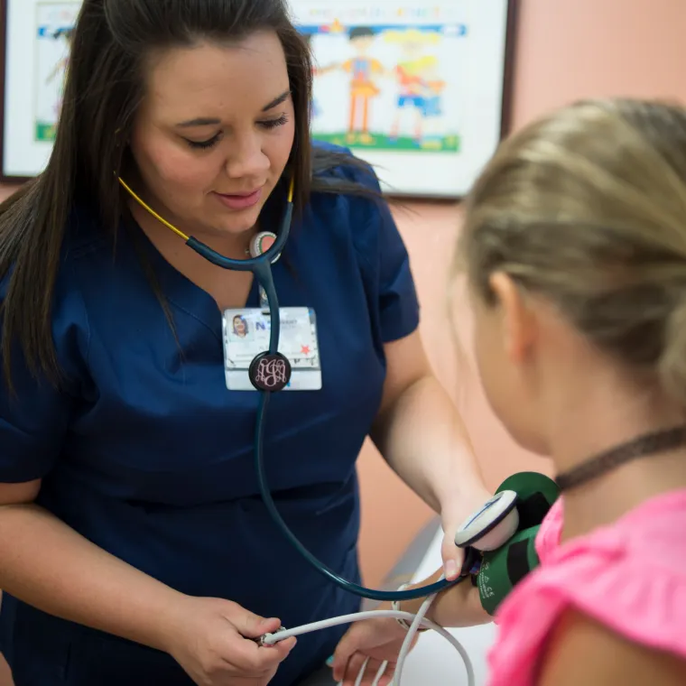 A Novant Health nurse is taking a young girls blood pressure.