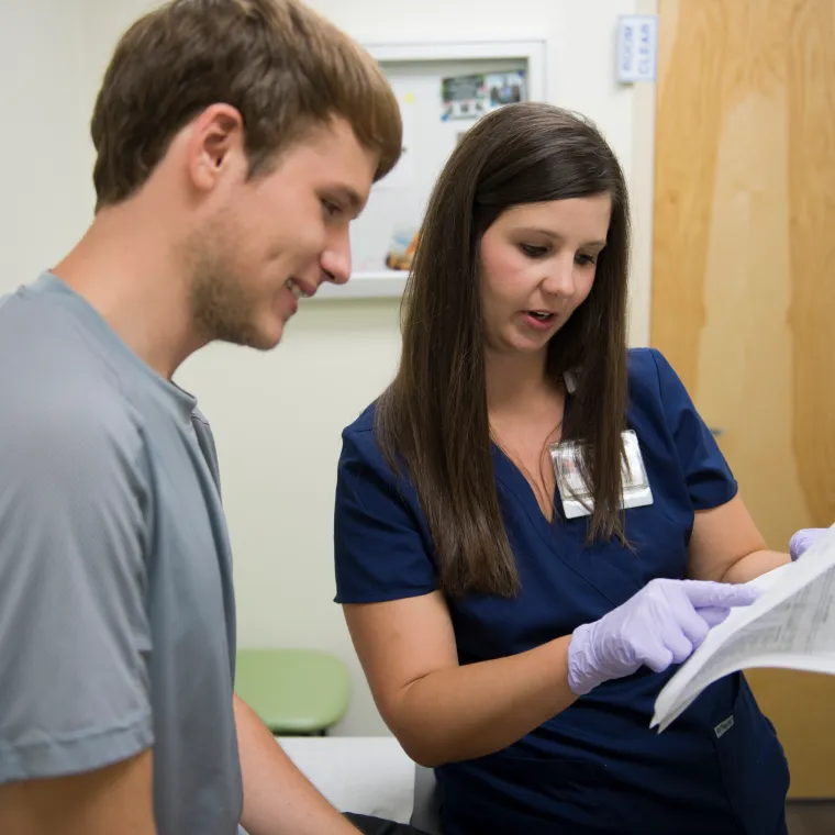 A Novant Health nurse is reviewing paperwork with a male patient.