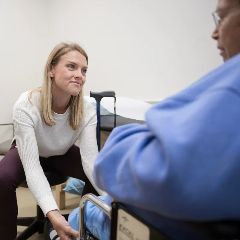 Dr. Harvey is bending over to exam a patient's ankle and foot