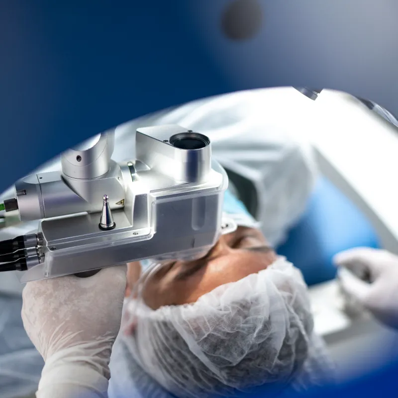 A healthcare provider is positioning a machine over a patient's eye during eye surgery. 