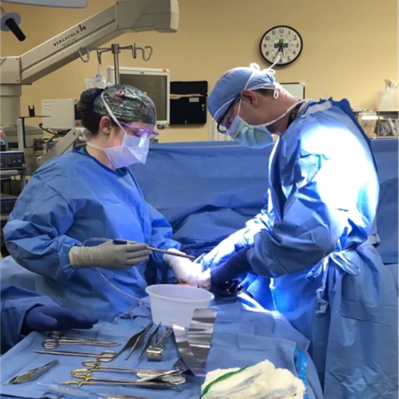 Two student residents are in an operating room performing a procedure. 