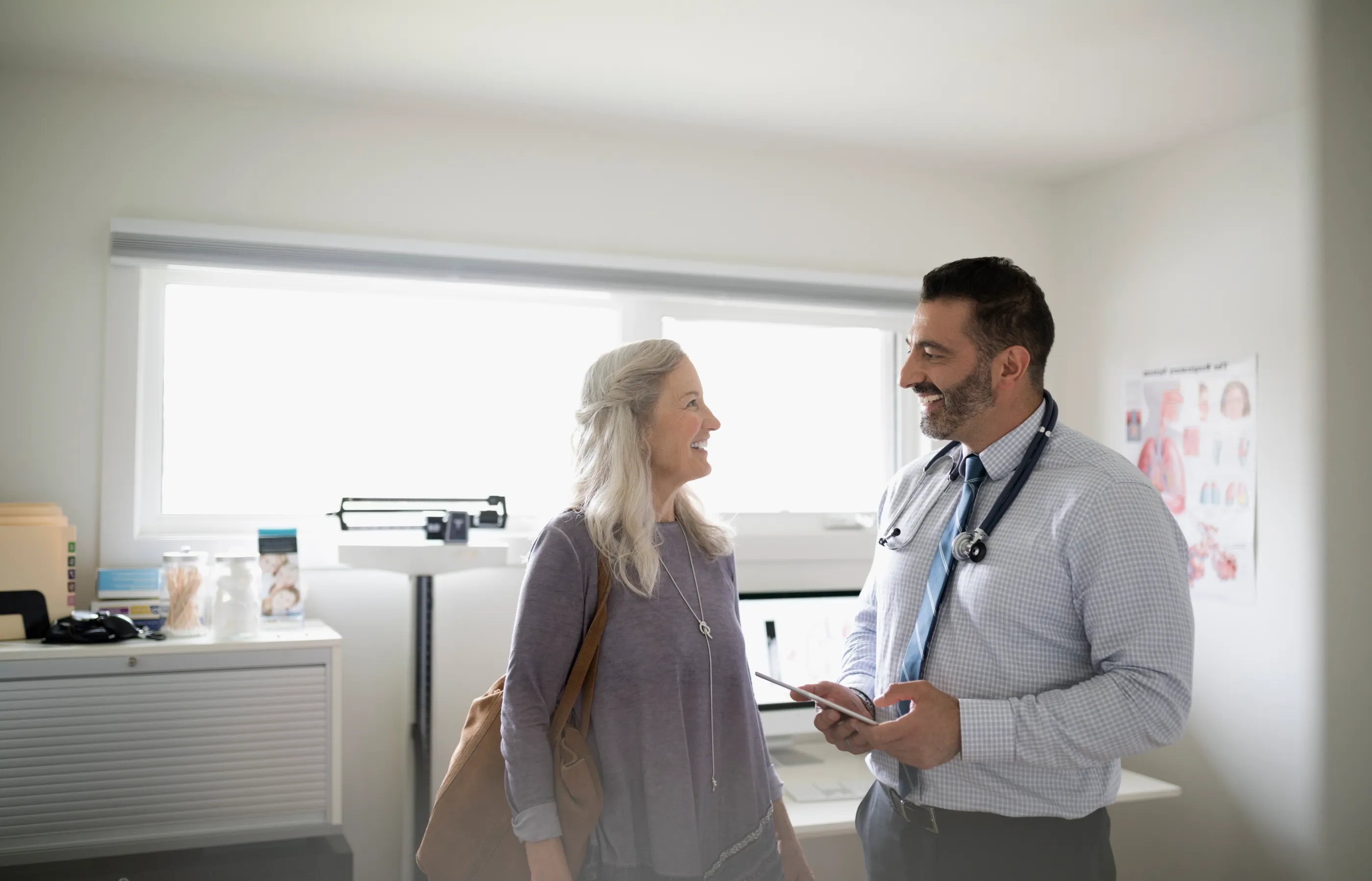 A woman is talking with her health care provider in an exam room. 