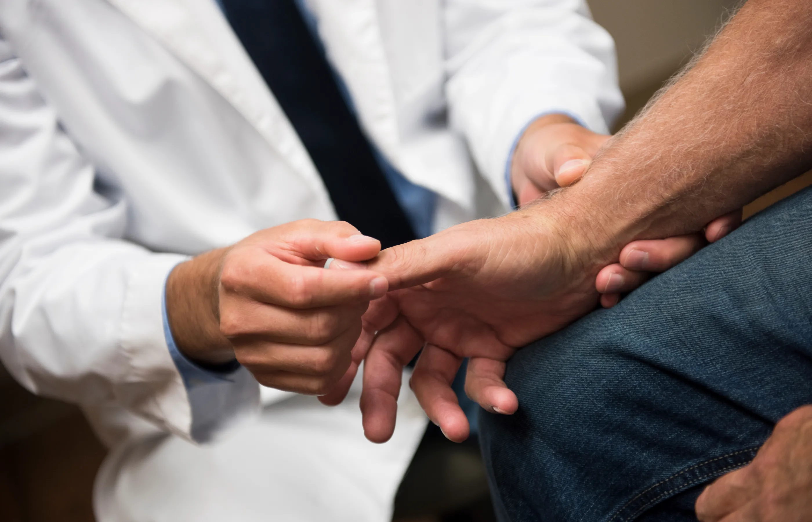 A doctor is examining a patients wrist and fingers. 